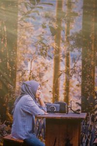 Side view of man sitting on seat in forest