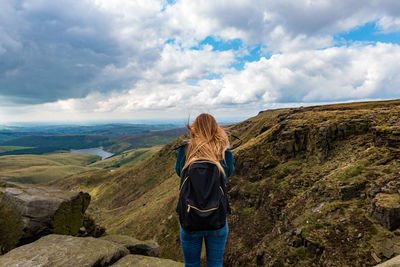 Rear view of woman standing with backpack on mountain