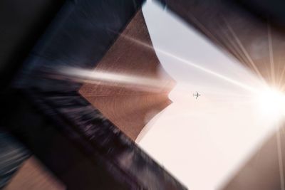 Low angle view of airplane flying against sky during sunny day