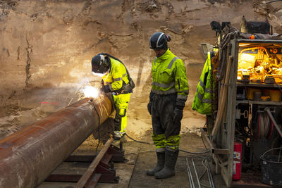 View of workers welding pipes at construction site