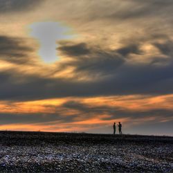 Scenic view of sea against cloudy sky at sunset