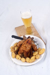 High angle view of roasted chicken with potatoes and beer in plate on table