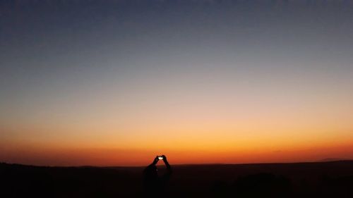 Silhouette person standing on field against clear sky during sunset