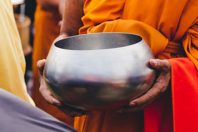 Midsection of monk holding container