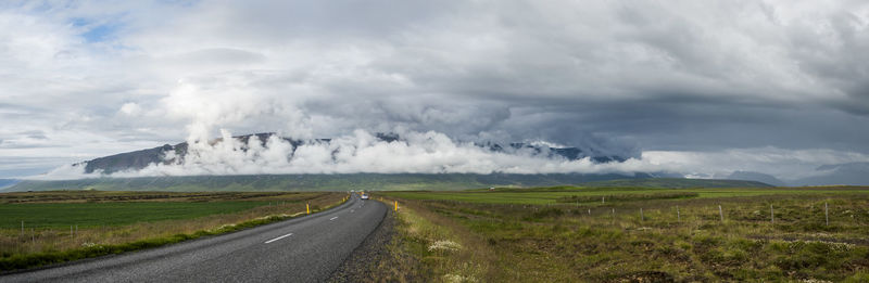 Road amidst field against sky