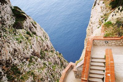 High angle view of staircase at rock formation by sea