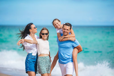 Smiling friends standing against sea