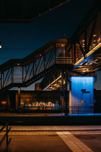 Illuminated bridge against blue sky at night