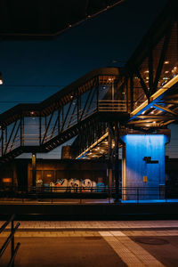 Illuminated bridge ah trainstation against blue sky at night