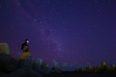 Low angle view of man sitting against sky at night