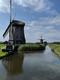Traditional windmill by water against sky