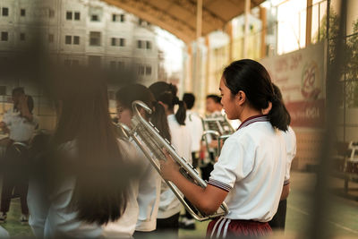 Side view of a young woman standing against the wall