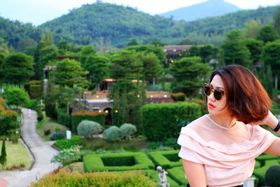 Young woman on sunglasses against trees on mountain