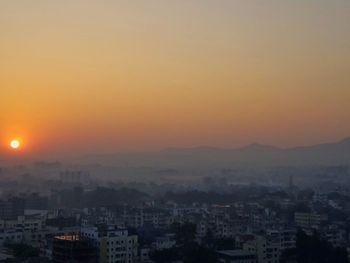 Buildings in city against romantic sky at sunset