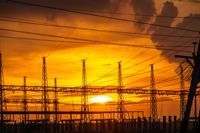 Low angle view of silhouette electricity pylon against sky during sunset