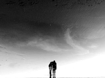 Rear view of silhouette man standing against sky