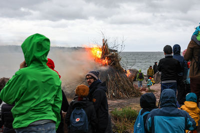 People standing by bonfire against sky