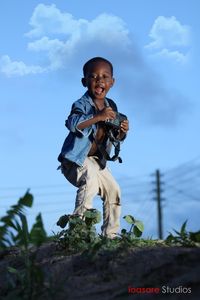 Full length of smiling boy against sky