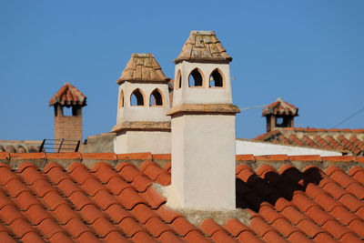 Chimneys on tile roof against blue sky