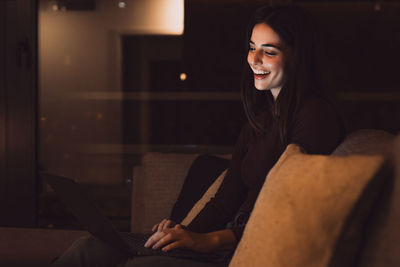 Portrait of young woman using phone while sitting at home