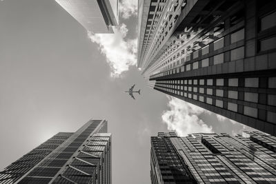 Low angle view of airplane flying over buildings against sky