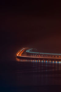 Illuminated bridge over river in city against sky at night