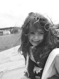 Smiling girl with tousled hair against sky