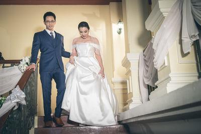 Portrait of bride and groom moving down on steps in building