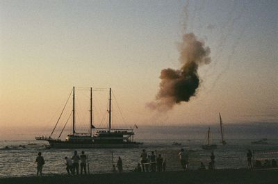 Sailboats in sea against clear sky during sunset