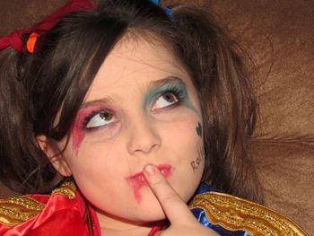 Close-up of thoughtful girl with messy face paint looking up