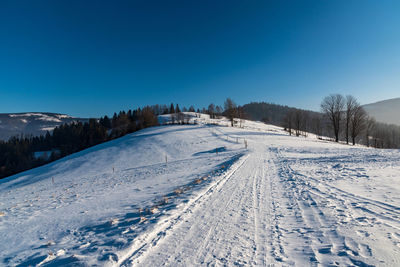 Snow covered landscape against blue sky