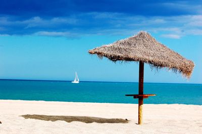 Thatched roof at beach against blue sky