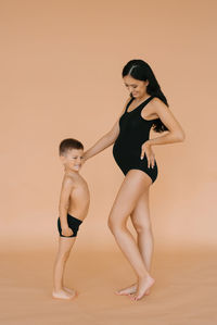 Happy motherhood. a pregnant woman in the studio on a beige background with her five-year-old son