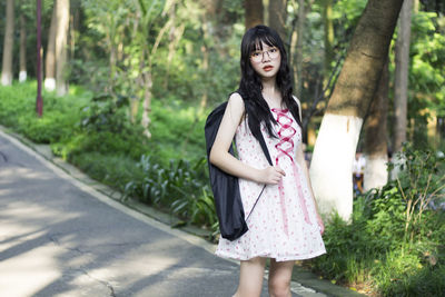 Beautiful young woman standing against trees