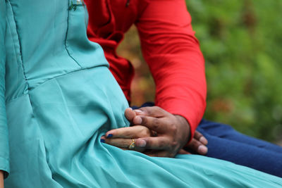 Midsection of husband with pregnant wife sitting outdoors