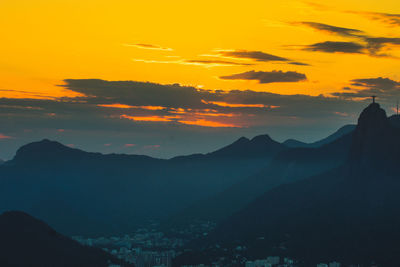 Scenic view of silhouette mountains against orange sky