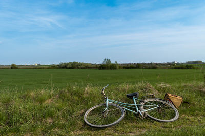 Bicycle parked on field against sky