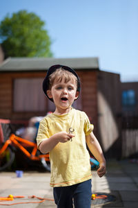 Portrait of 2 years old boy playing in his back yard on warm sunny summer day.
