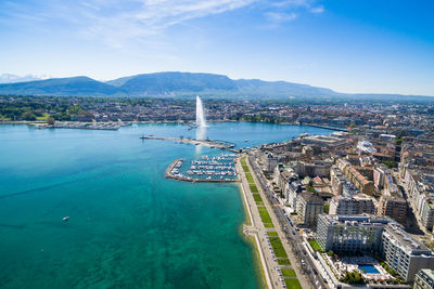 Aerial view of cityscape by sea against blue sky