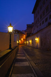 Illuminated street lights by buildings in city at night