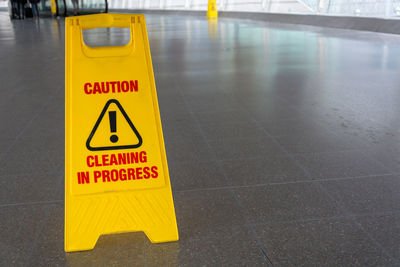 Close-up of warning sign on tiled floor