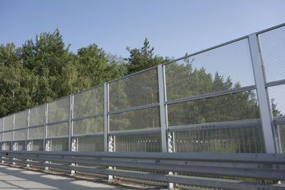 Fence by trees against clear sky