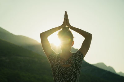 Midsection of woman standing by mountain against sky