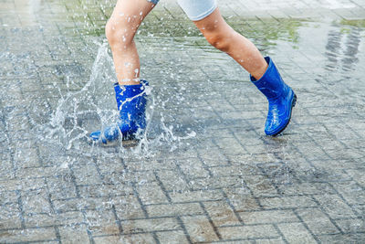 Low section of person running on puddle during rainy season