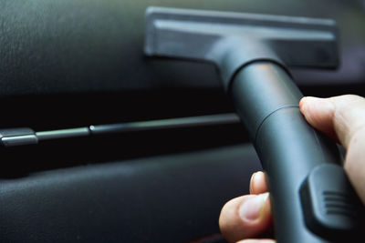 Cropped image of man hand cleaning car with vacuum cleaner