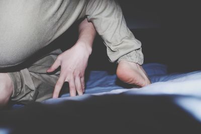 Low section of man sitting on bed