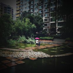 Reflection of woman walking on wet puddle in city