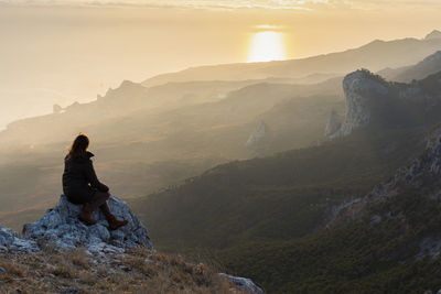 A girl stands on a mountain and looks at the sunset. atmospheric evening view of the mountains