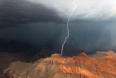 A bright lightning bolt strikes a cliff in the grand canyon during a summer thunderstorm.