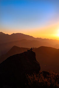 Silhouette person on mountain against sky during sunset